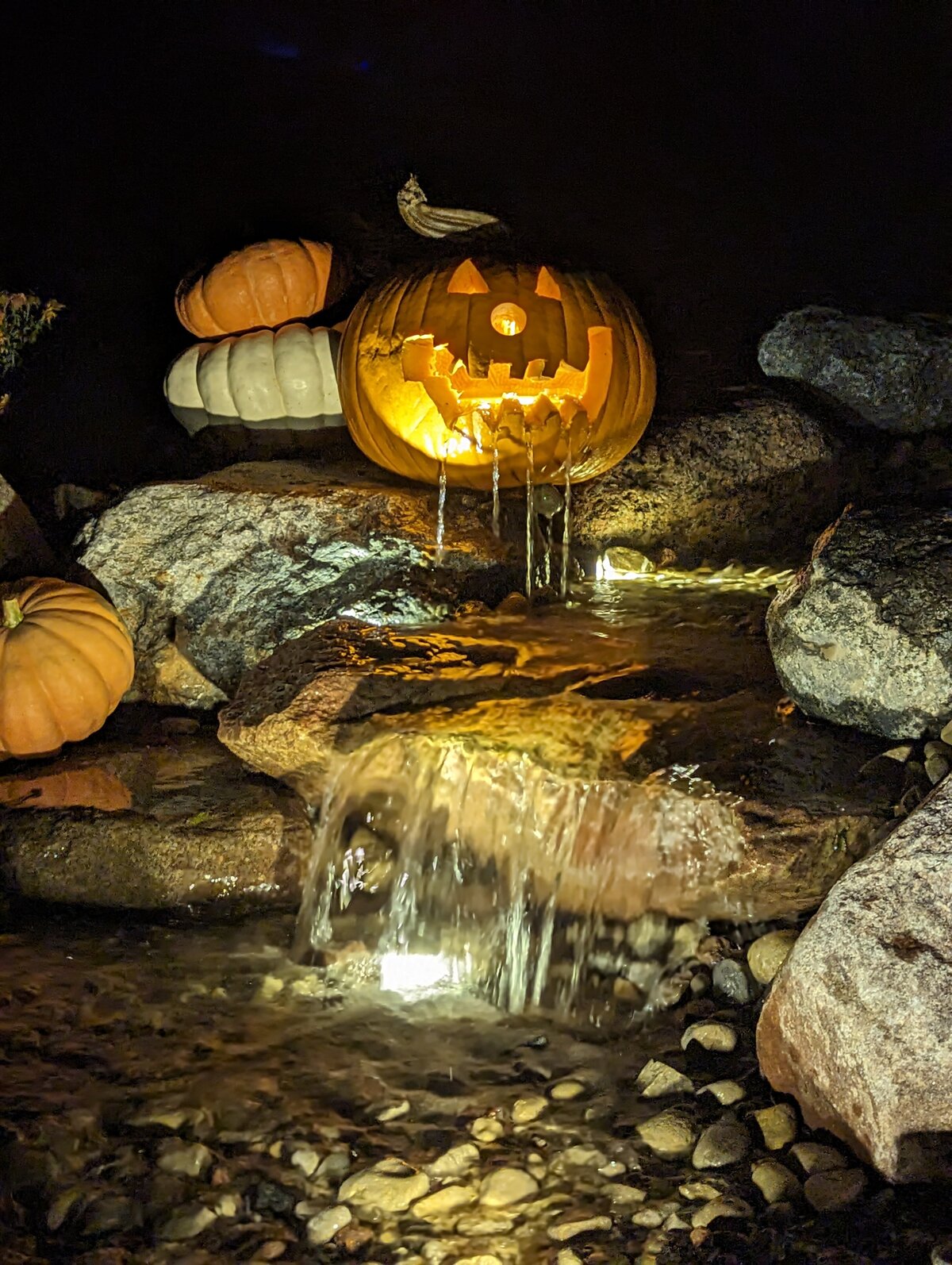 Carved Jack O'lantern spilling water from it's mouth into waterfall below