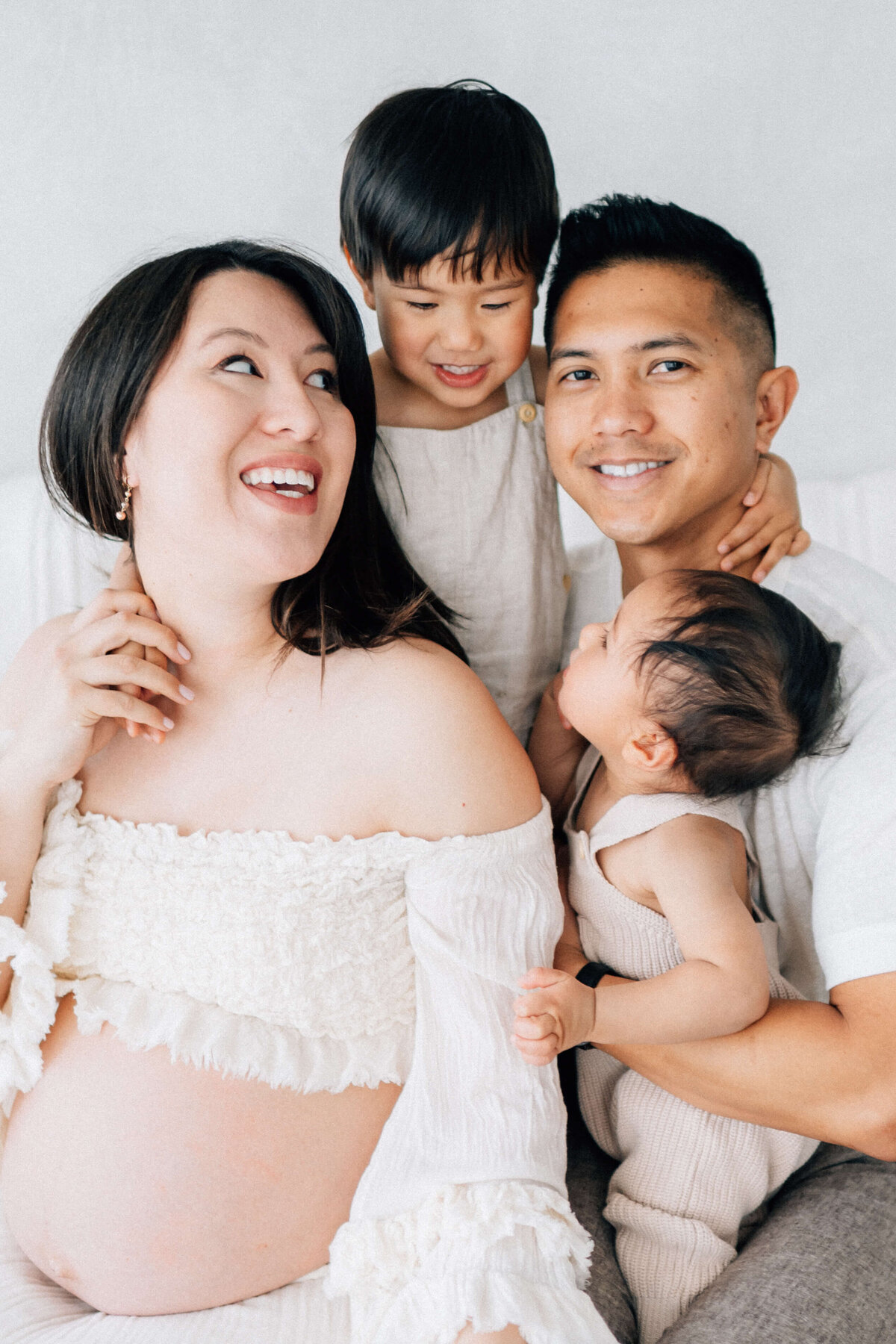 a family of four gathered around their pregnant mother looking at Denver photographer