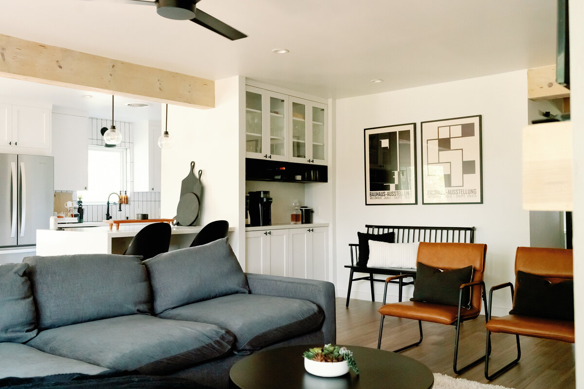 living room with bar cabinet built in, gallery wall, gray couch and brown leather chairs