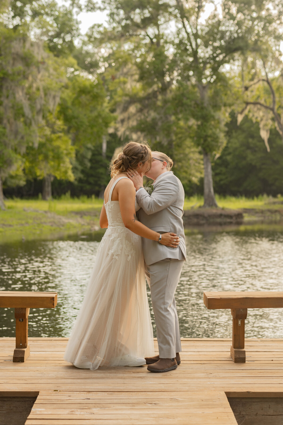 LGBTQ brides kissing on dock at Cypress Creek  Farmhouse in Astatula Florida by Florida wedding photographer Amanda Richardson Photography