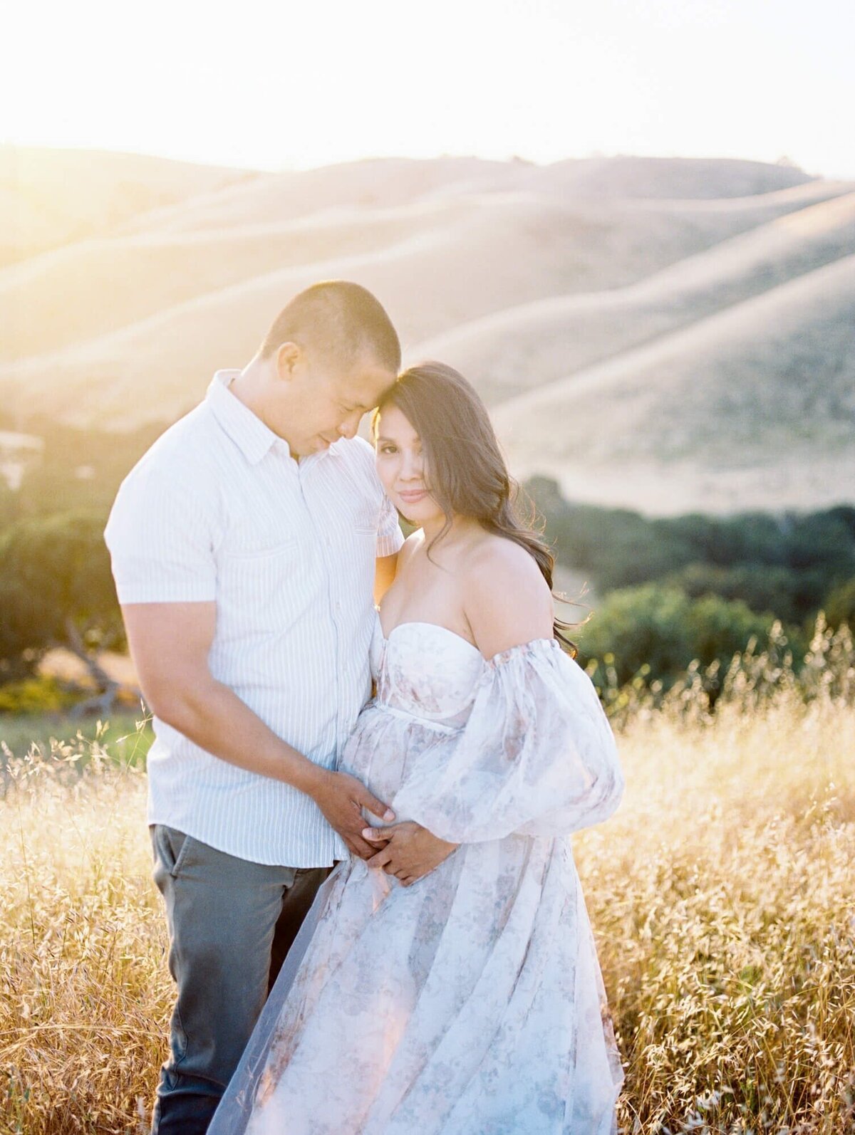 Pregnant woman and her husband framing her belly in a tulle dress taken by one of the top San Francisco Maternity Photographers Laurel Smith.