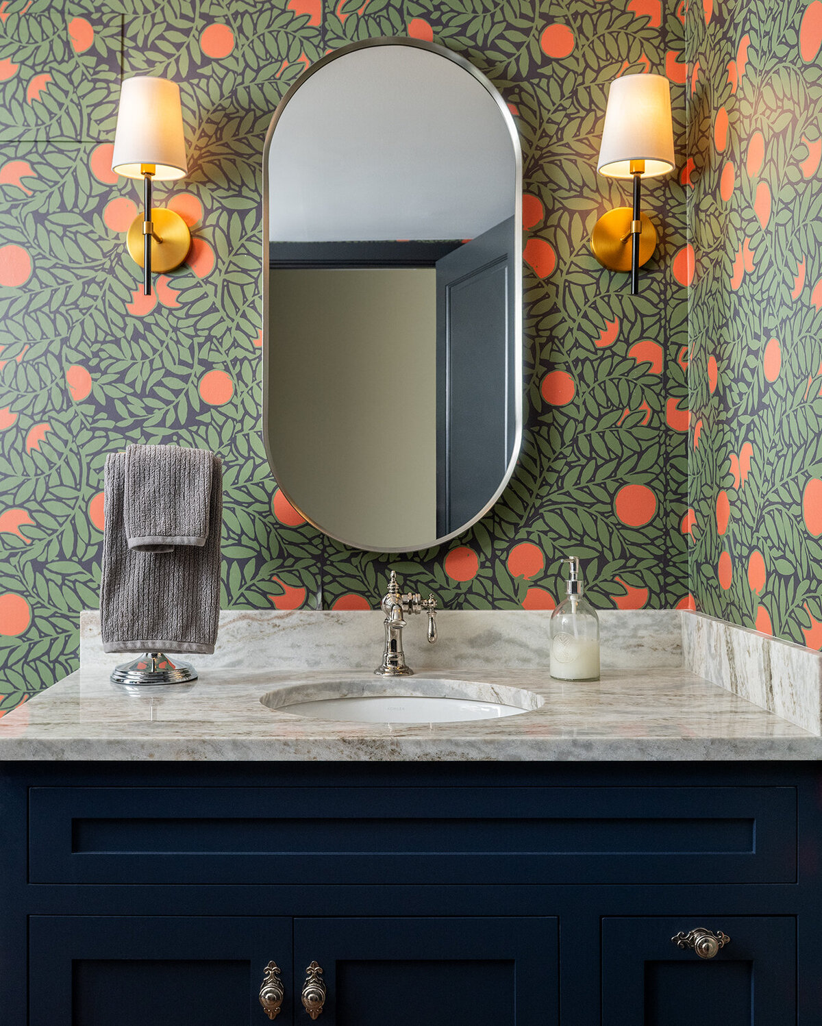 marble sink with orange and green patterned wallpaper
