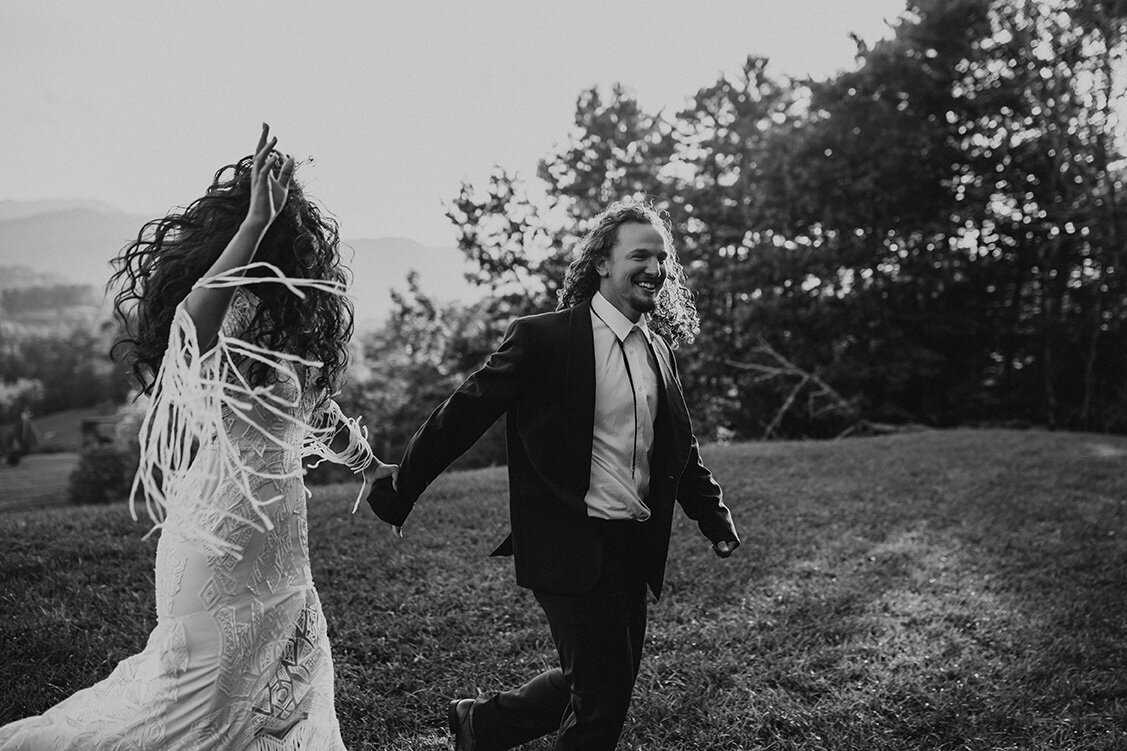 bride and groom wearing a wedding gown and suit while running outdoors