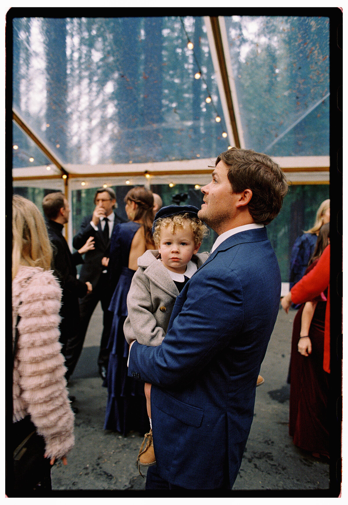 A nostalgic film photograph of a child waiting quietly beneath the redwoods before the ceremony at Nestldown in Santa Cruz, captured in Kate Winters’ elegant, documentary style