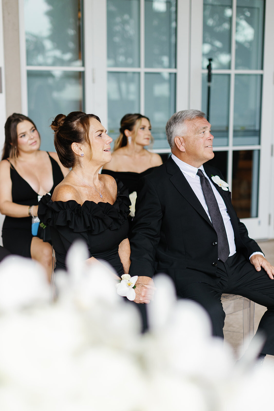 The bride's parents, seated in the front row, visibly emotional as they watch the ceremony at Ocean Reef in Key Largo, beautifully captured by Claudia Amalia Photography.