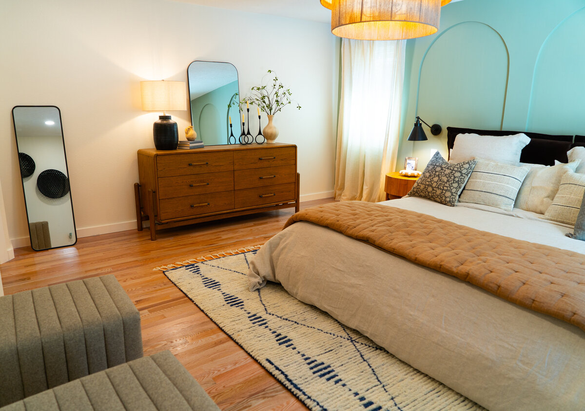 luxury bedroom with white dresser white sitting chiar and bed with blue blanket