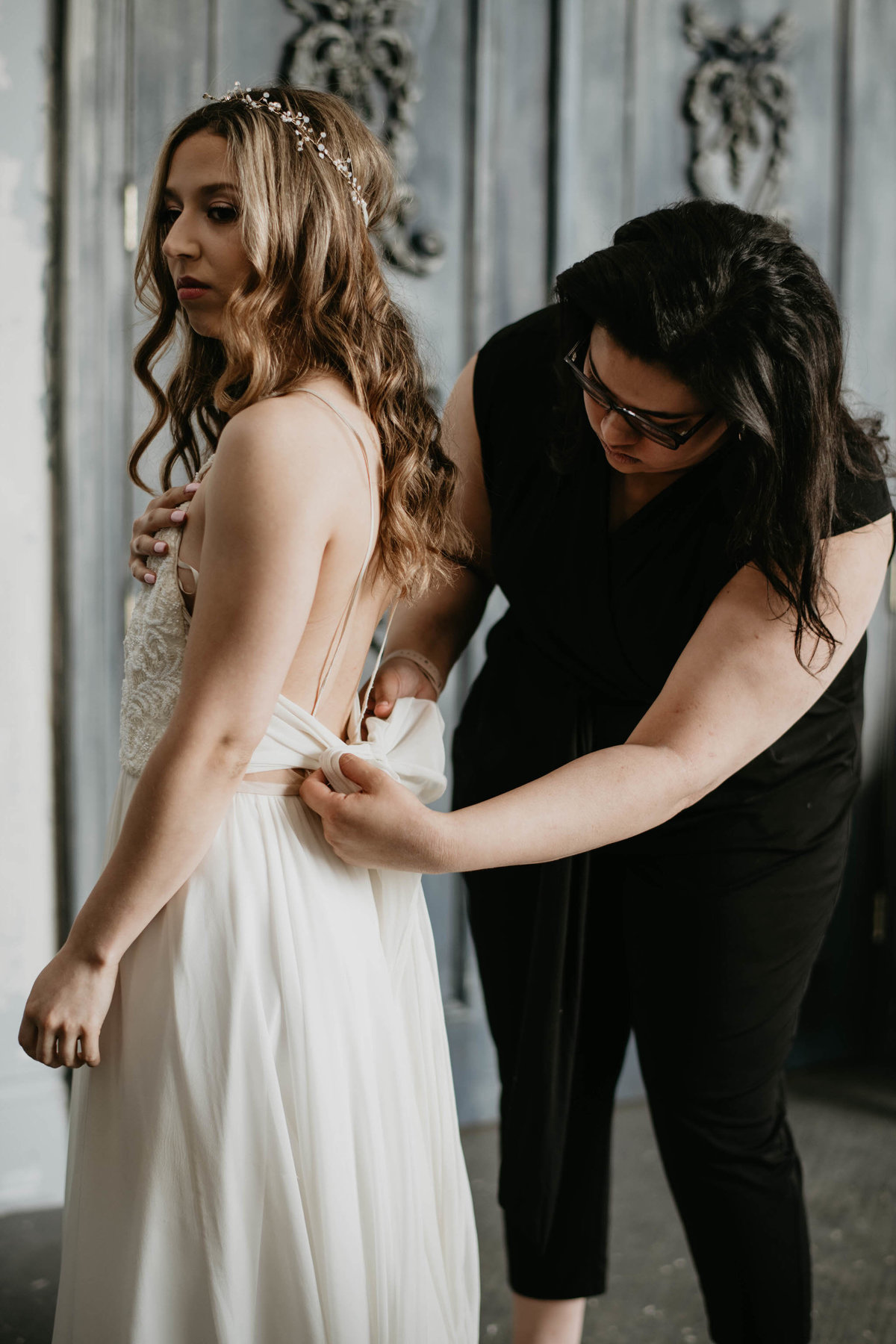 wedding planner tying wedding dress for her bride