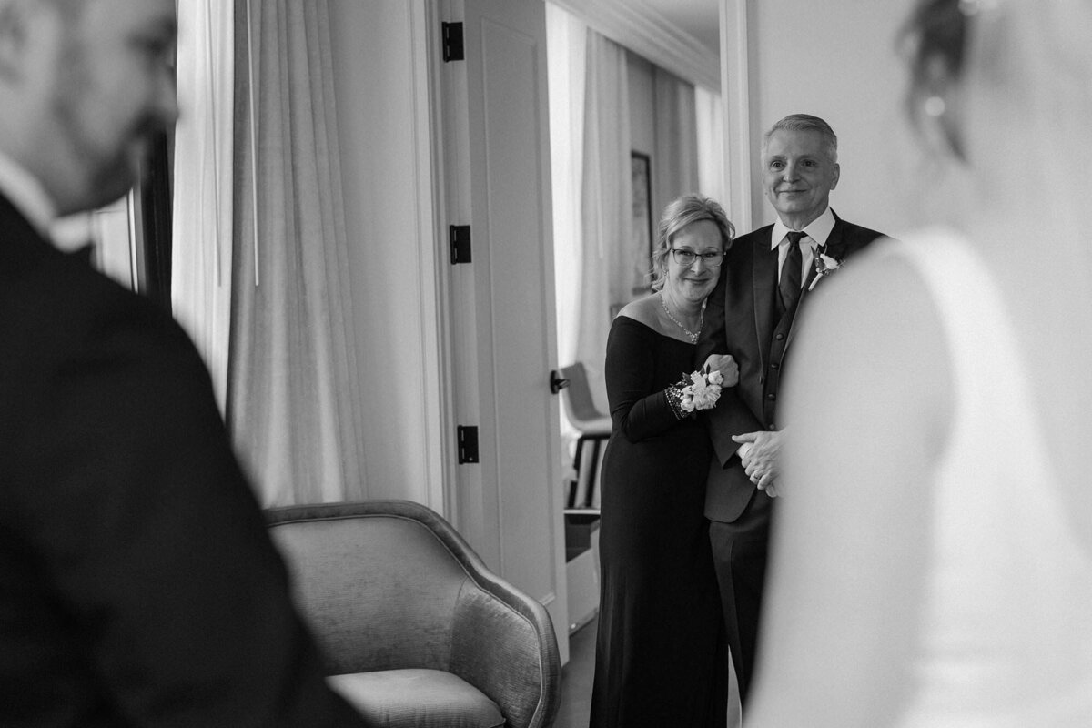 Parents smiling as they look at their child on a wedding day 