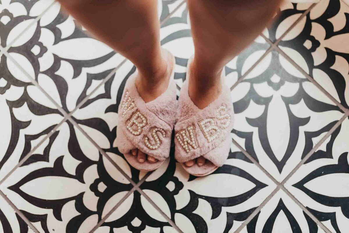 Brides monogrammed slippers against a black and white print floor.