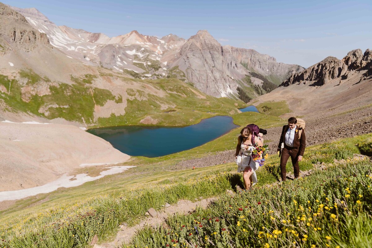 Couple hikes on a rocky trail surrounded by the dramatic peaks of Ouray, Colorado.