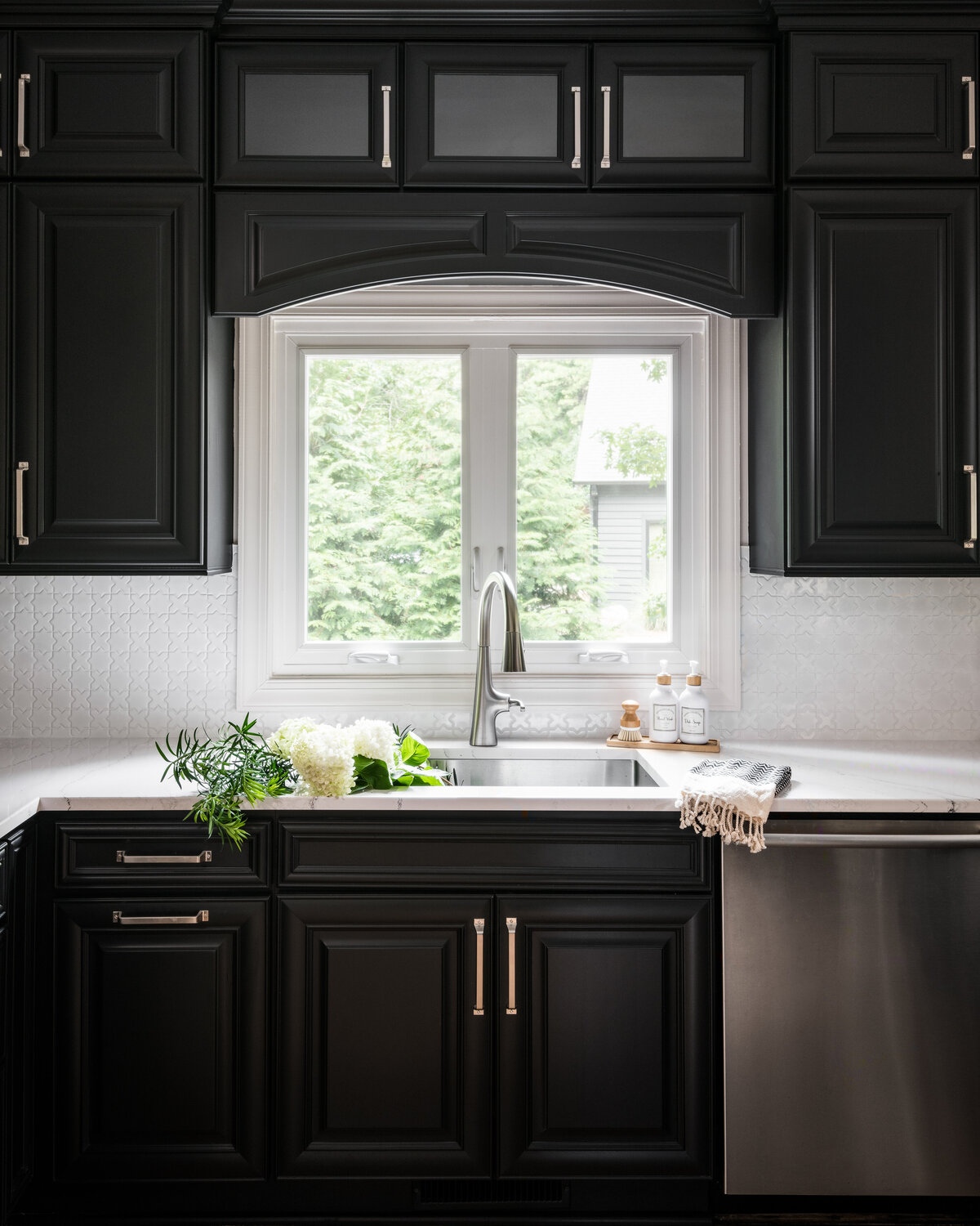 Modern kitchen in Lake Norman, NC, featuring black cabinetry, a bright window, and sleek finishes.