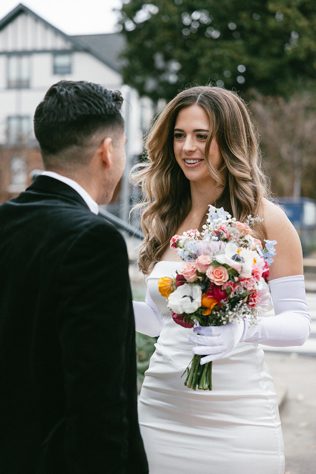 Bride smiles mid sentence as she holds her elopement day bouquet and looks at her new husband. 