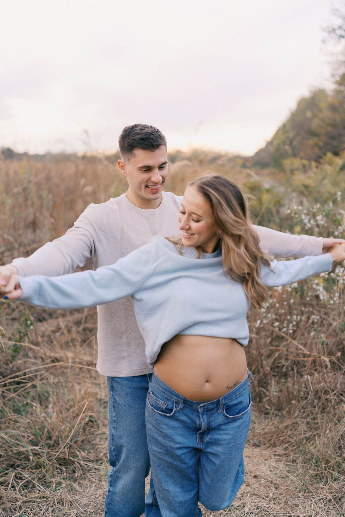 pregnant woman holds hands with man in golden field near knoxville tennessee