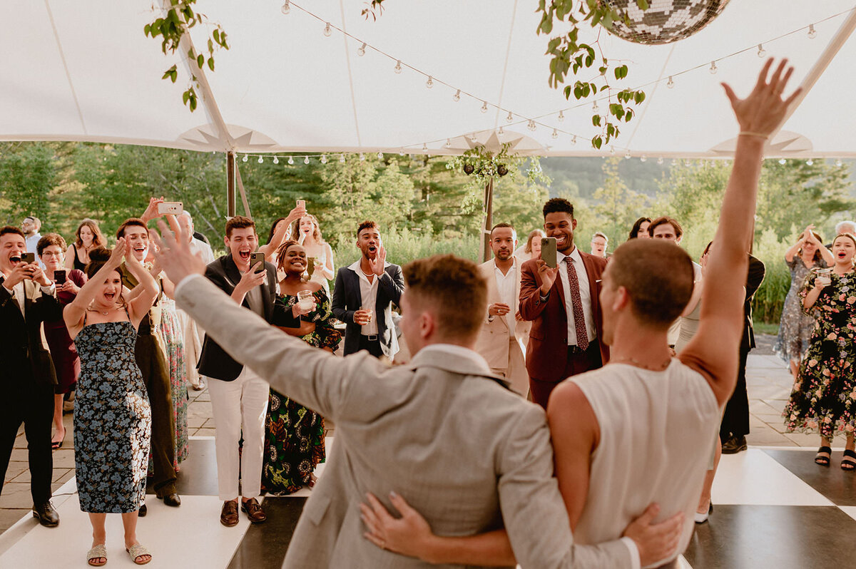 grooms-enter-tented-wedding-reception-guests-cheer