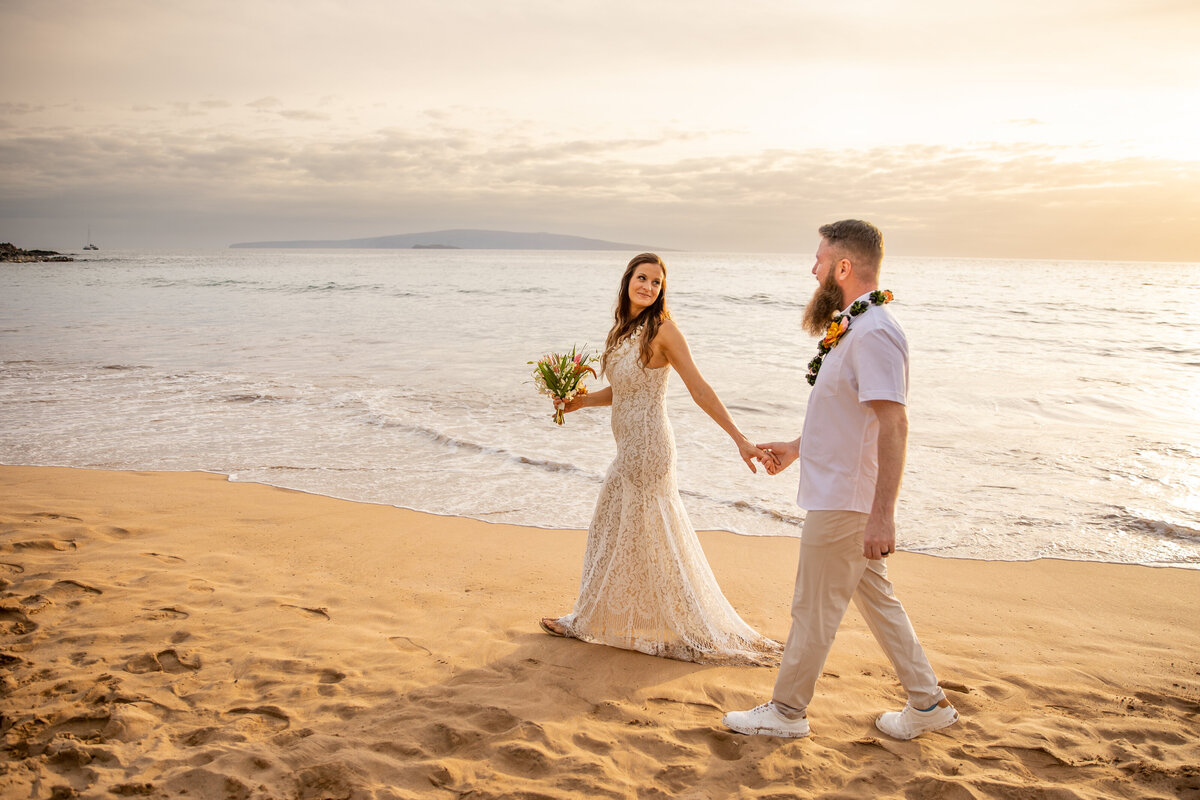 Maui Wedding Photographer captures bride and groom holding hands walking on sandy beach