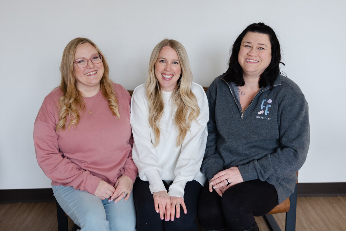 Three women seated together, smiling in a studio branding session. Photograph by Yucaipa branding photographer Kaitlyn Dawn Photography.