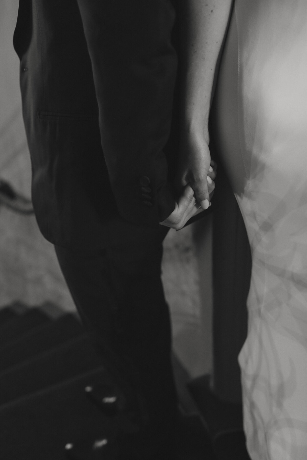 bride and groom holding hands during first touch photo in black and white