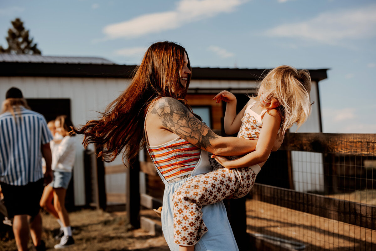 Mom swings daughter on hips while their hair flies in the wind