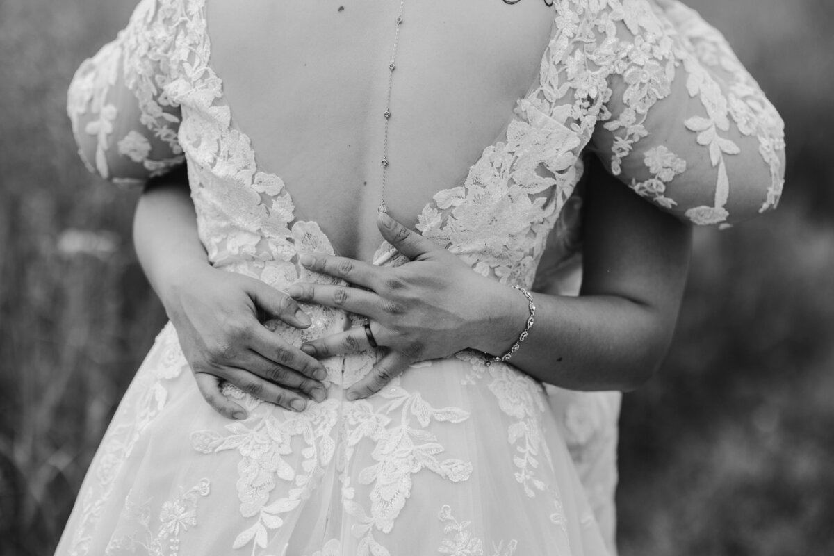 black and white photo of arms wrapped around the back of a bride