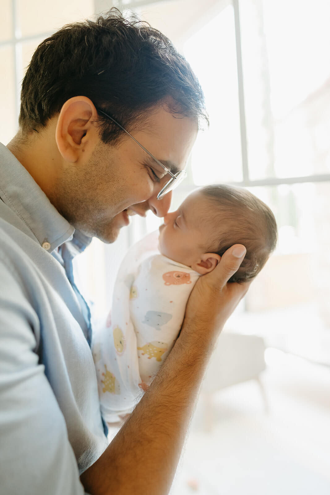 Walnut Creek in-home newborn photography with mom and dad holding baby near window.