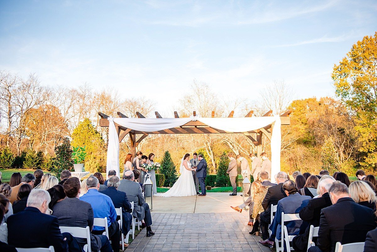Fall wedding under the large ceremony arbor on the island in the center of the lake at Sycamore Farms in the fall in Tennessee