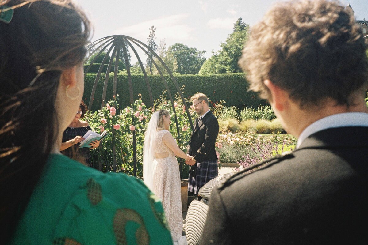 A wedding ceremony photographed between two people. The image is grainy and captured on 35mm film.