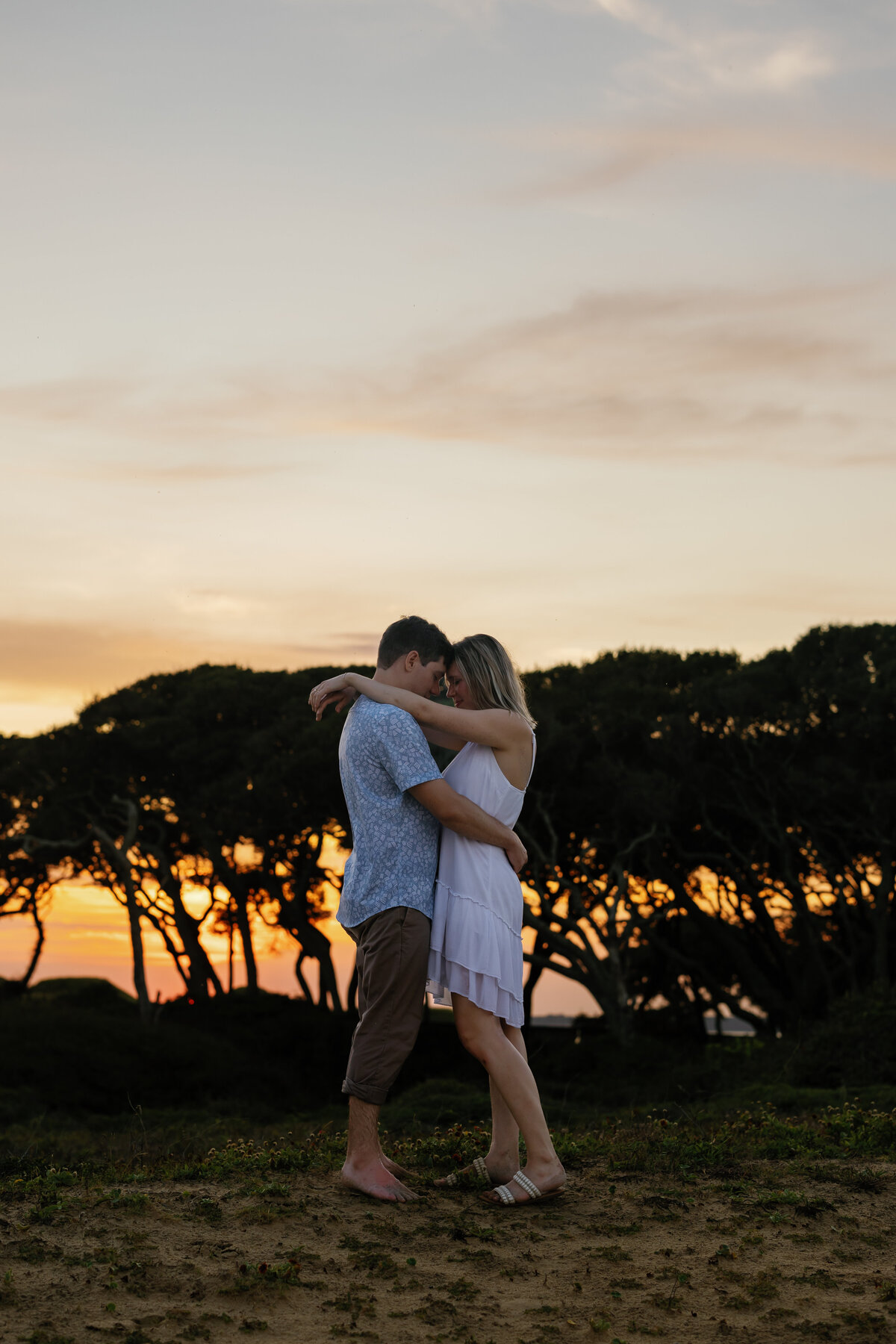 Couple embracing at sunset on Wilmington beach, romantic engagement portrait