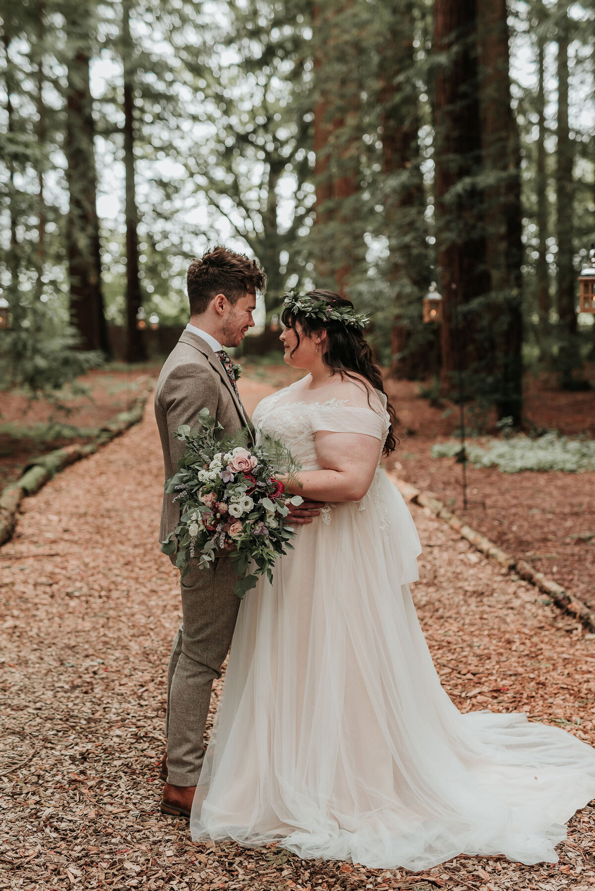 Bride and Groom holding whimsical bridal bouquet in the woods at their romantic woodland wedding at Two Woods Estate