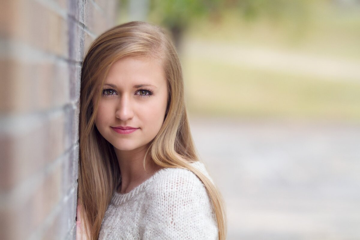 Senior girl leaning against a brick wall in Fayetteville.
