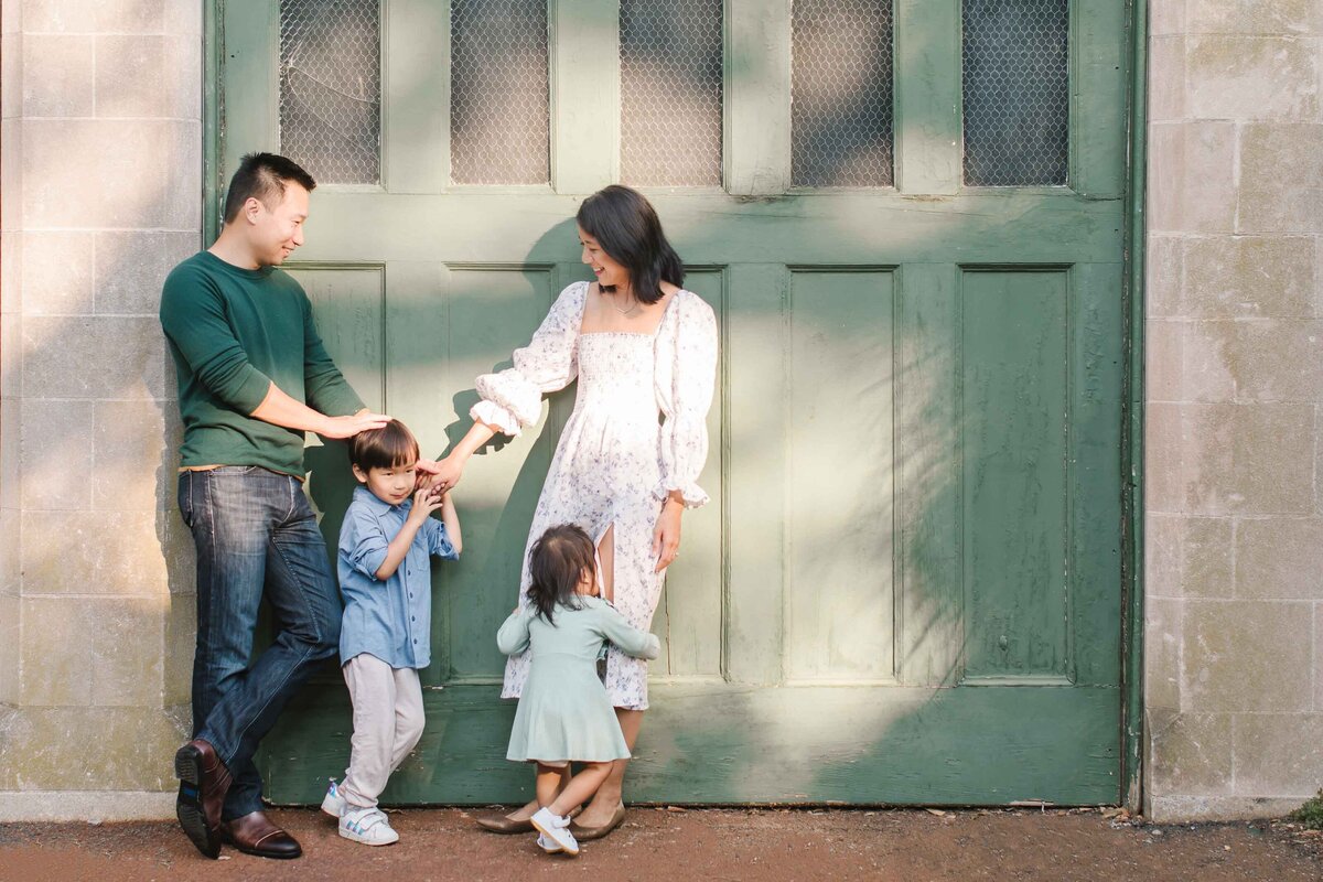 family of four standing against green garage door
