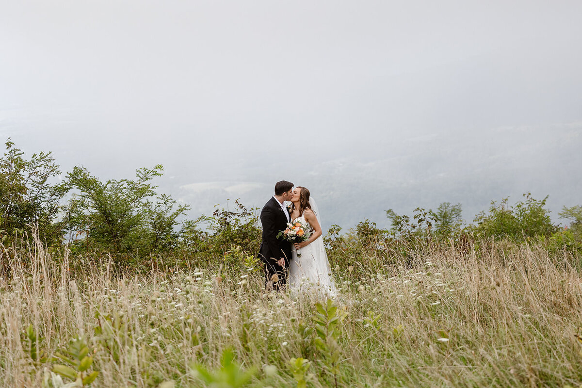 A newlywed couple kissing in a field