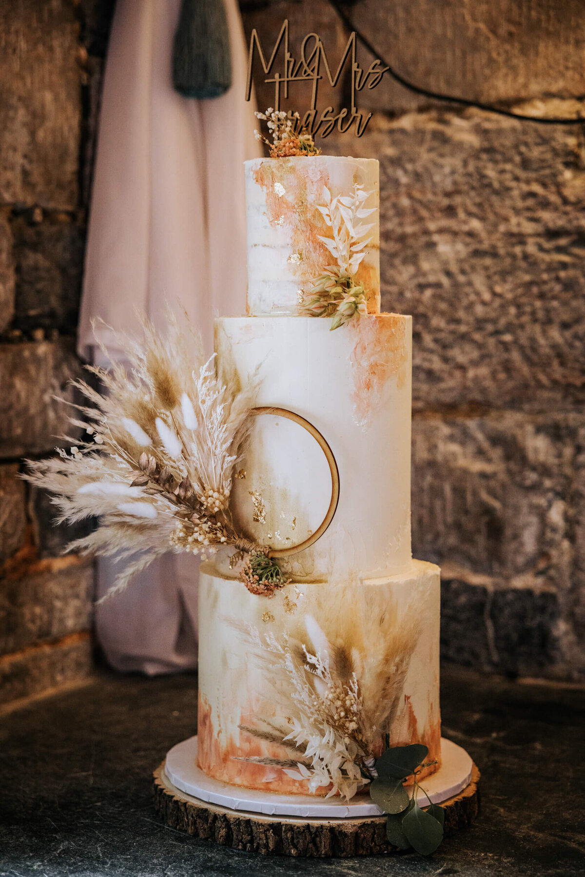 A wedding cake decorated with feathers and a ring