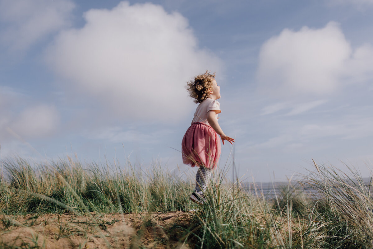 little-girl-jumping-in-sand-on-beach