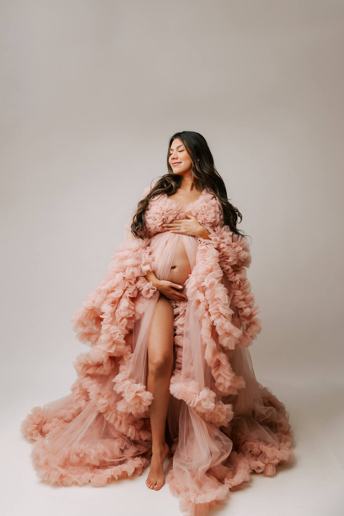 fine art portrait of mom wearing tulle couture gown that is pink inside studio maternity session in oregon by photographer ann marshall.
