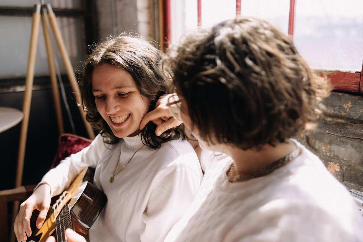 LGTBQ couple, woman playing guitar as other woman touches her neck