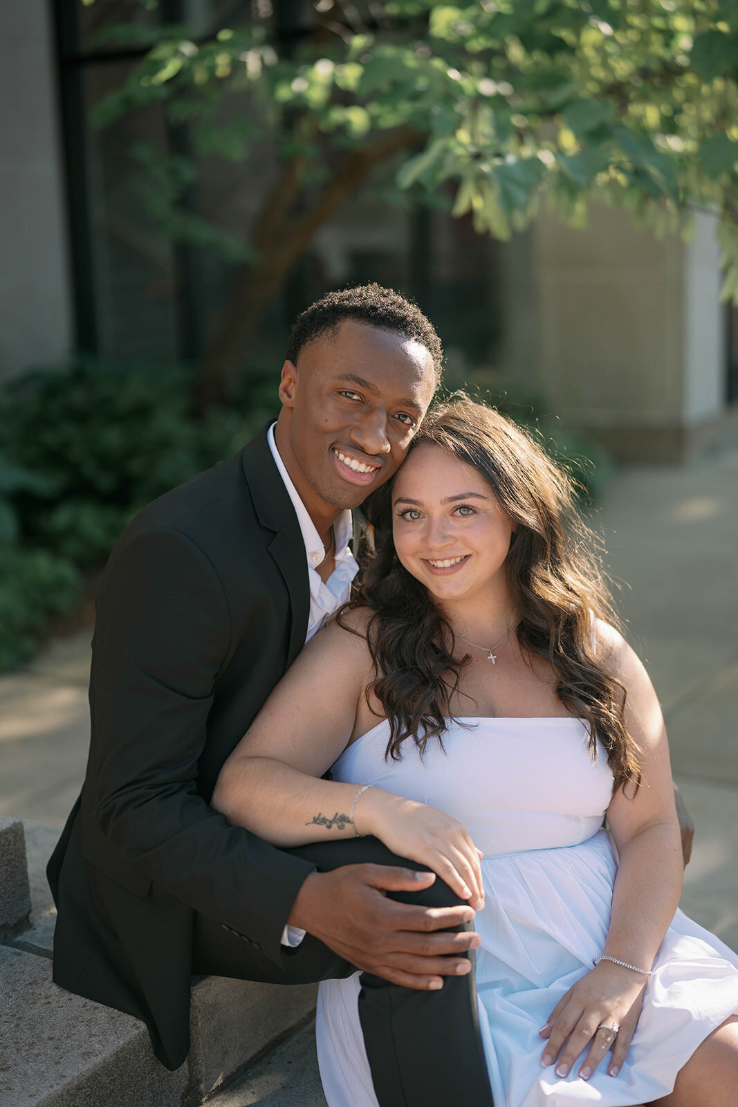 Classic engagement portrait of couple sitting together on stone steps in Kalamazoo, MI.