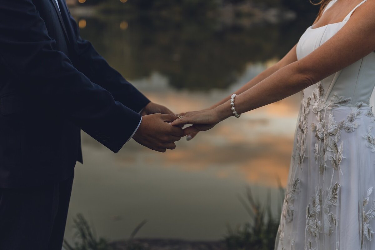 Groom pulling bride close for kiss under moody sunset sky
