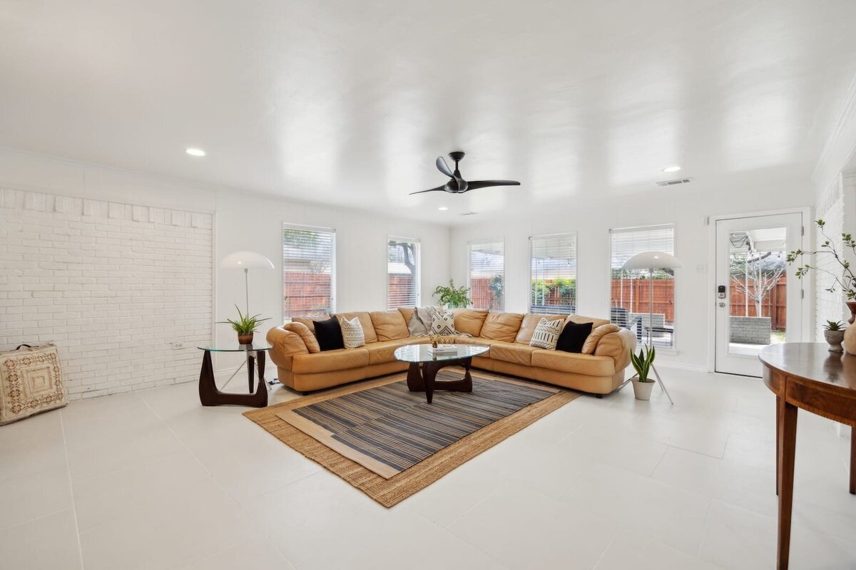 Bright sunroom at 3120 Chapel Downs Dr Dallas TX featuring leather sectional, white painted brick walls, and tile floors — listed by Haven Realty Group.