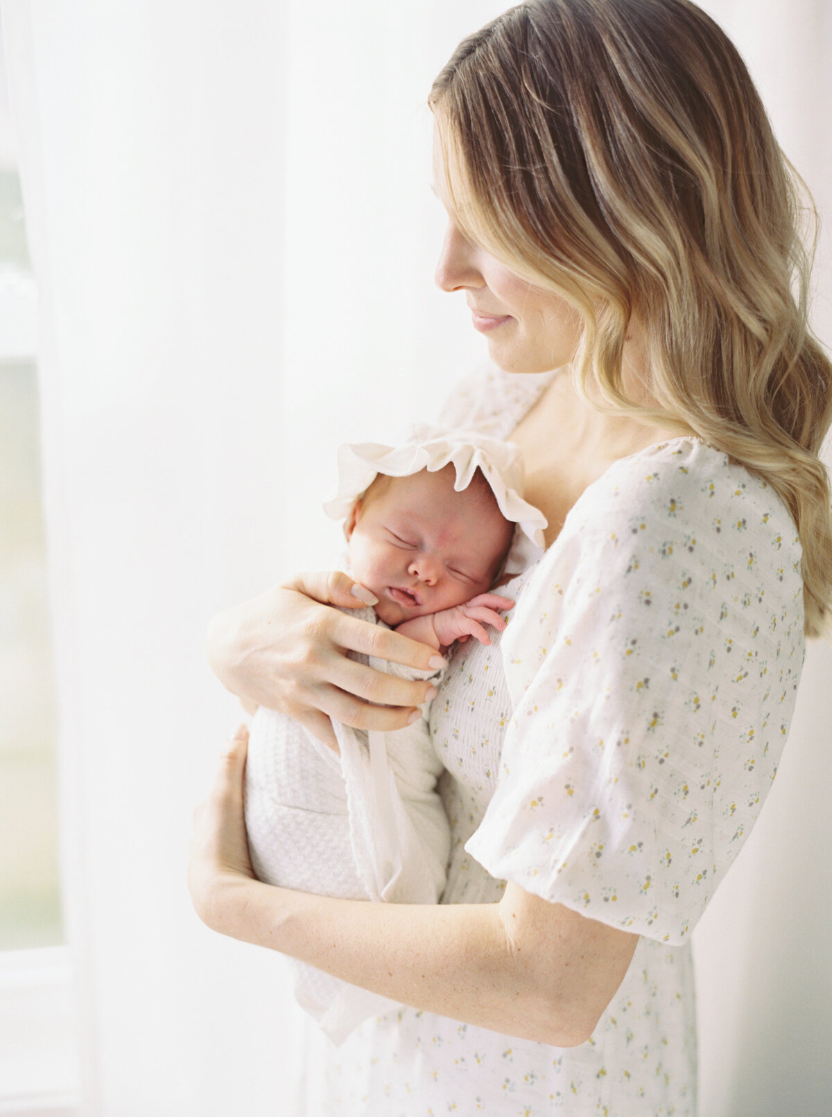 newborn baby girl in all white on master bed by photographer in madison wi talia laird photography