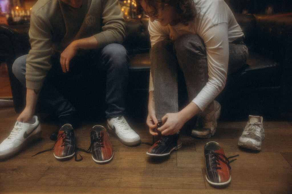 A couple putting on bowling shoes.