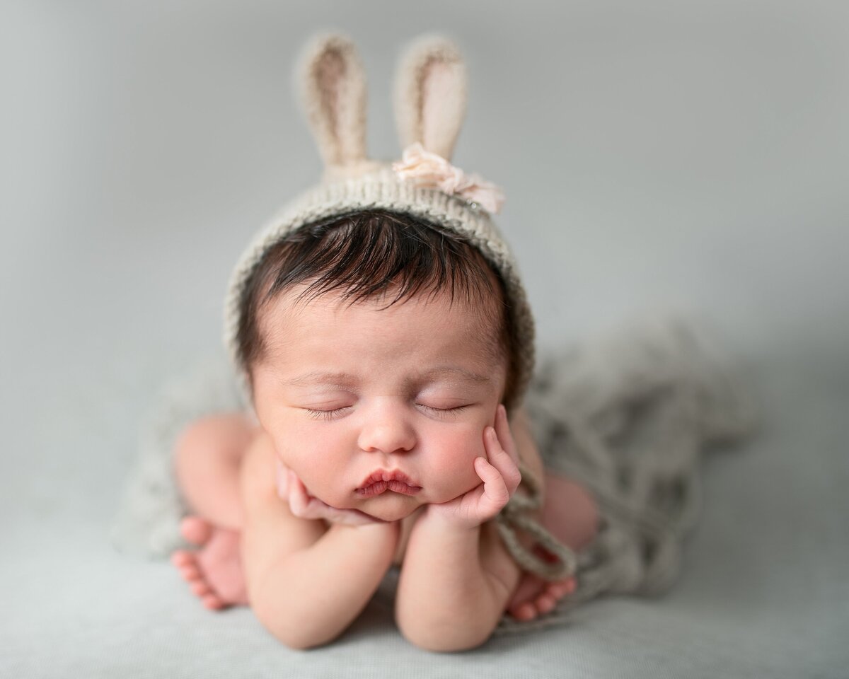 froggy pose of newborn girl wearing bunny bonnet