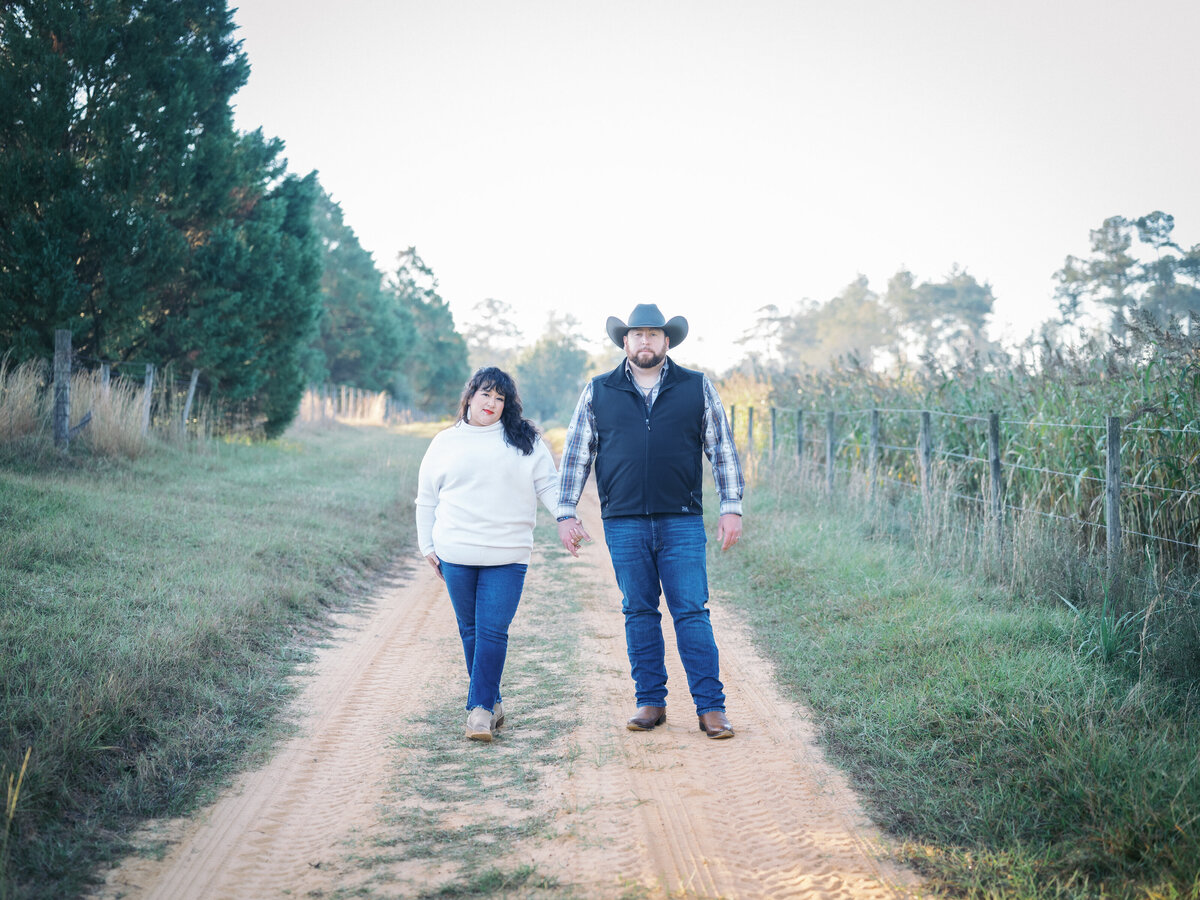 A couple walking hand in hand down a dirt road during a romantic outdoor session near Tallahassee, FL 