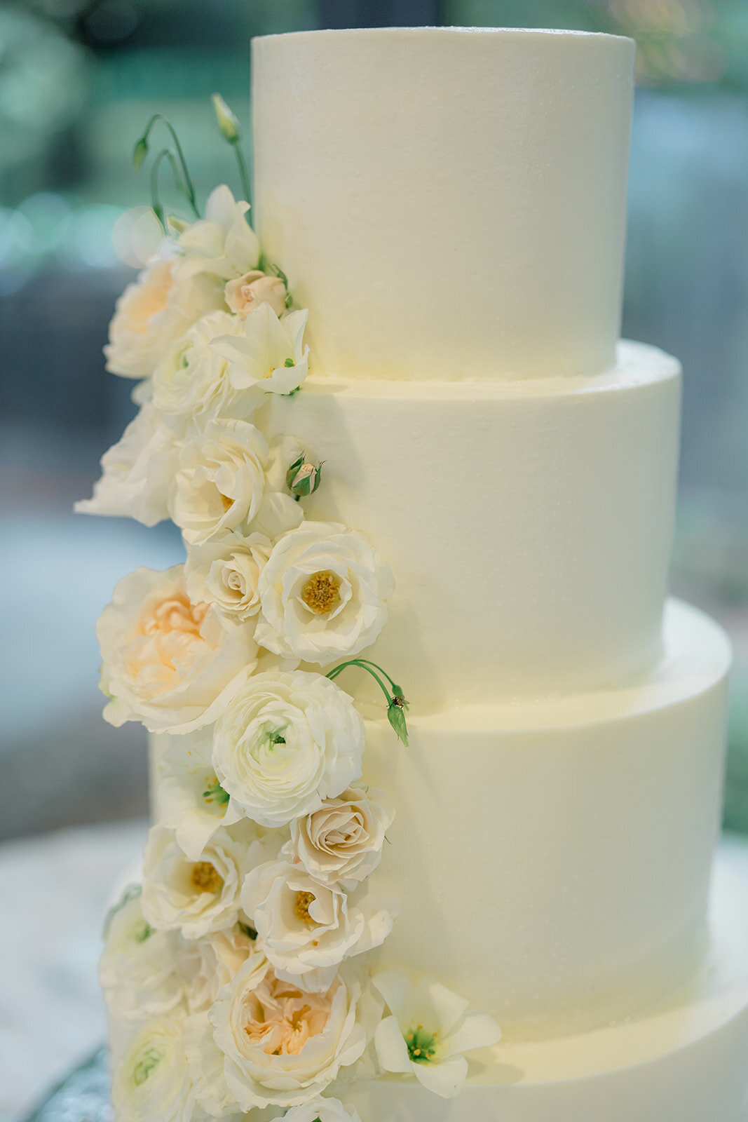 White Buttercream wedding cake decorated with soft peach and white flowers. 