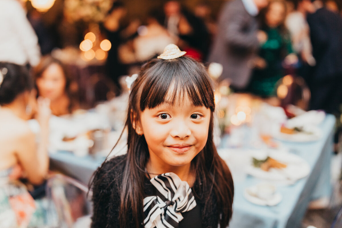 little girl wears a cute party hat on top of her head during the reception