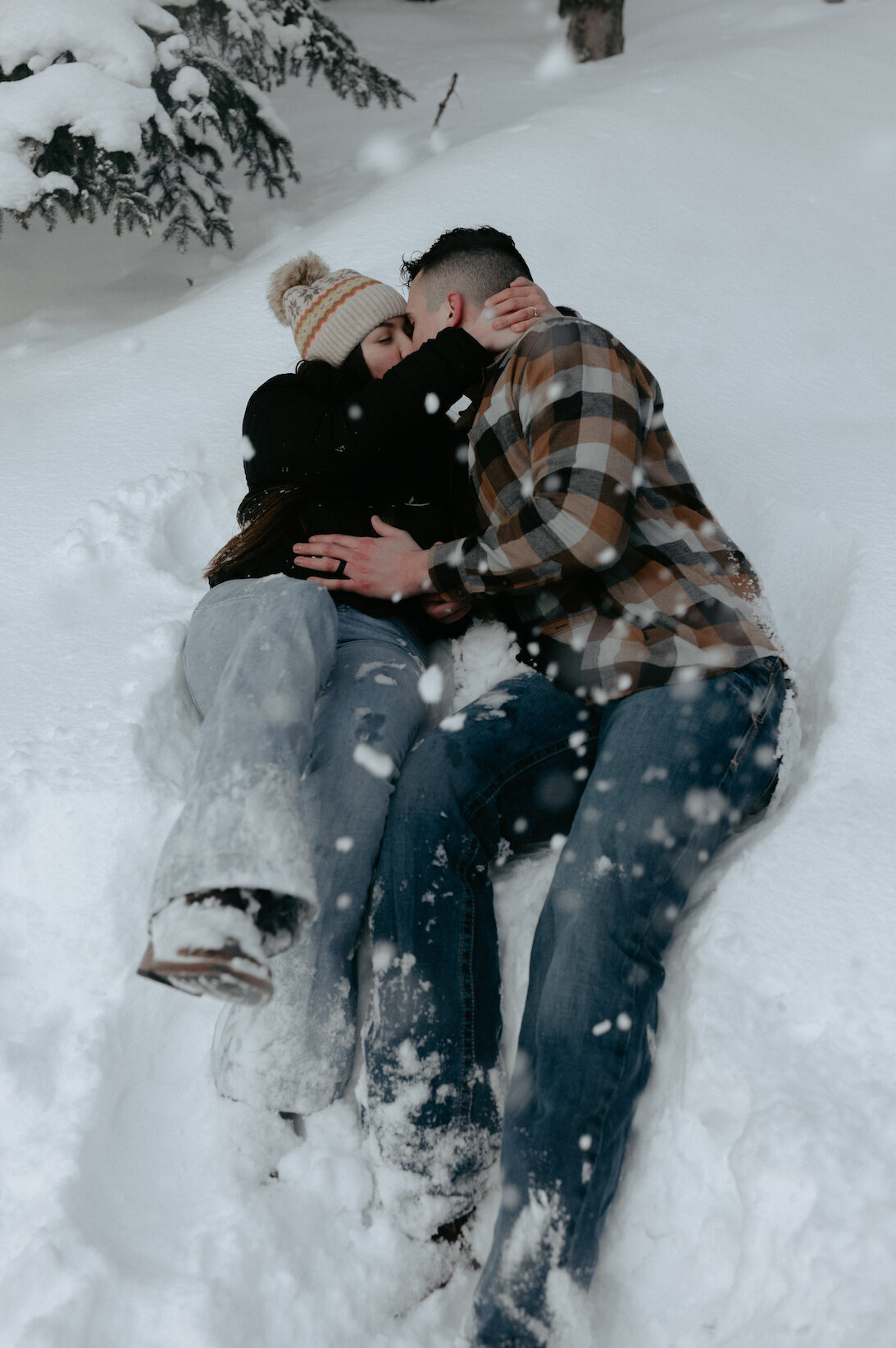 Couple rolling around in the snow with one another.