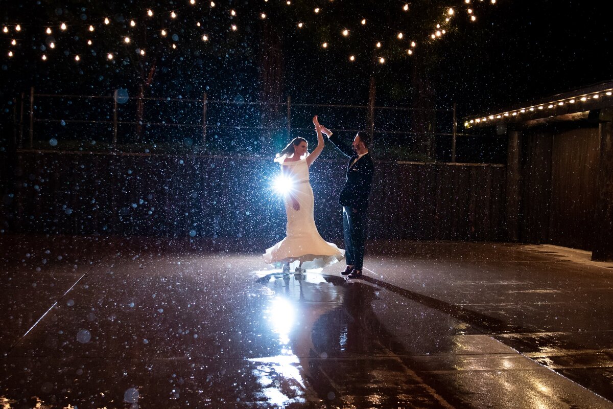 Bride spins with groom after their reception in the rain in Colorado.