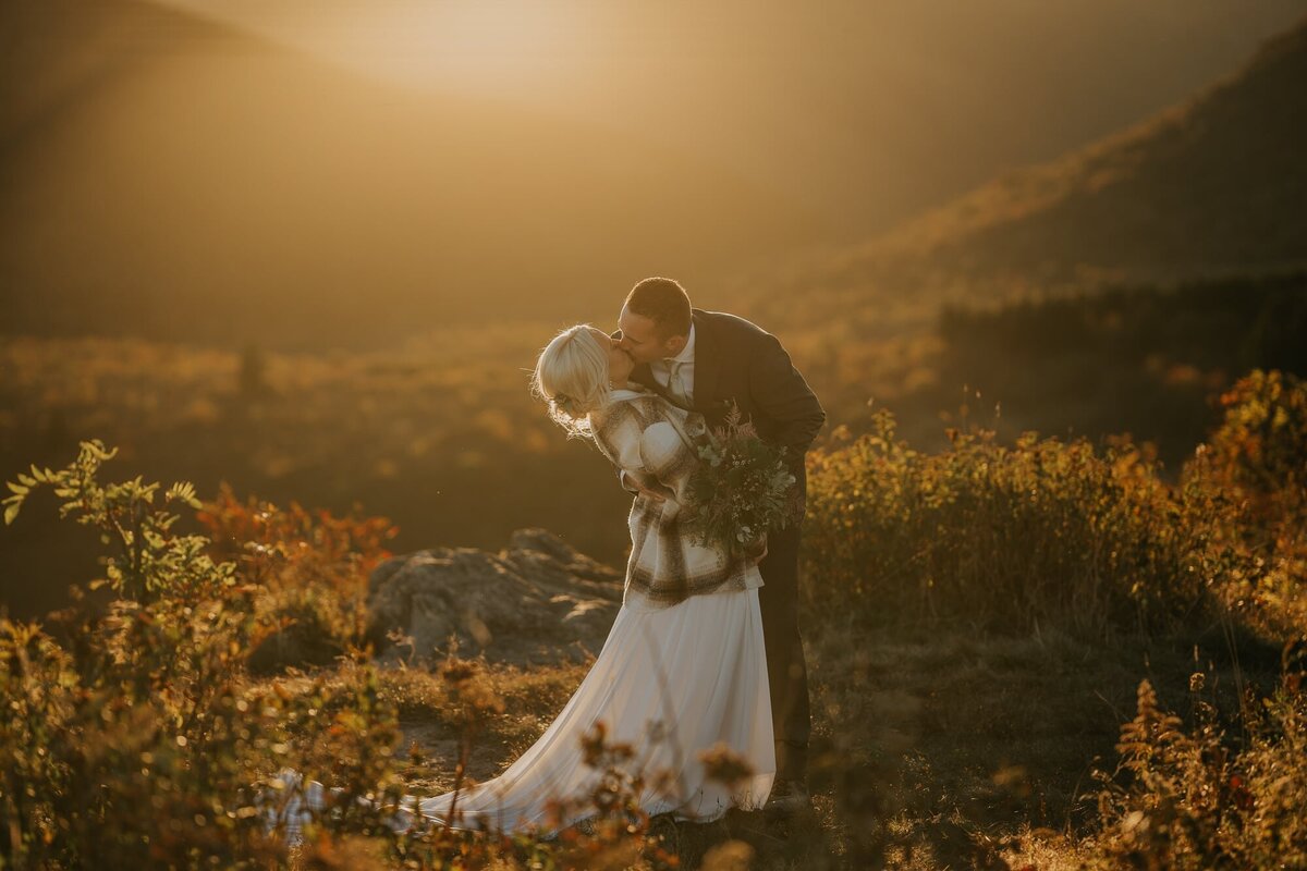 Couple eloping in the mountains sharing their first kiss