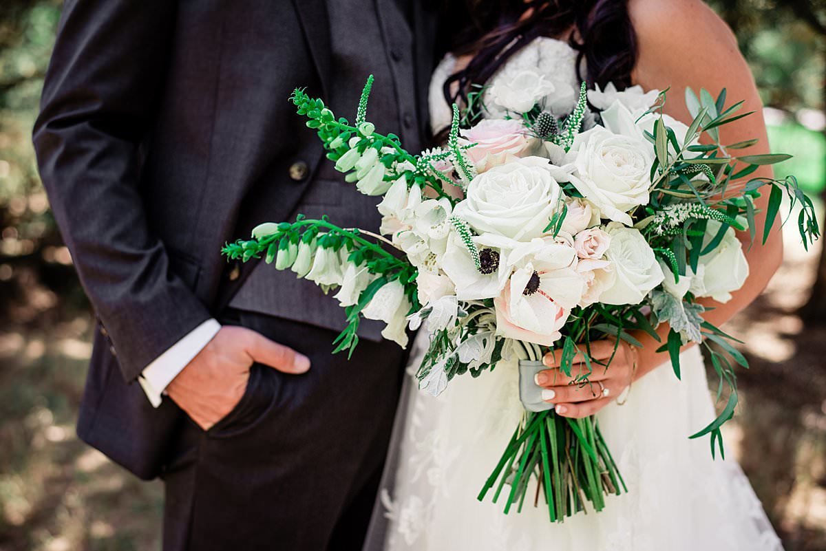 Close up photo bride holding her neutral colored bridal bouquet next to her groom