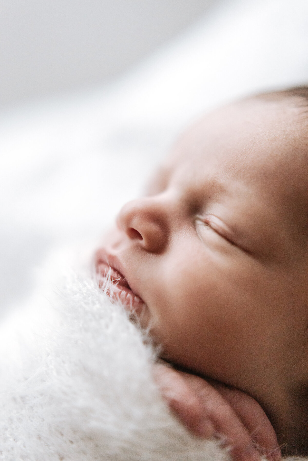Baby boy sleeping in a white blanket in newborn photoshoot in Billingshurst