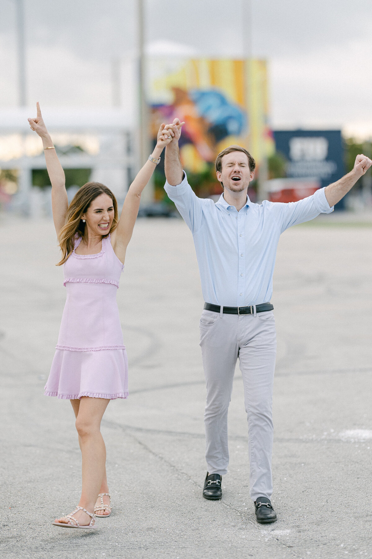 Happy couple cheering and celebrating, holding hands and smiling during an outdoor engagement session by Rodrigo Varela Photography.